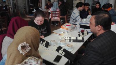 Sprachcafé Drei Frauen und ein Mann sitzen an einem Tisch und spielen ein Buchstabenspiel